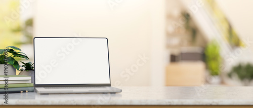 Φωτογραφία White screen laptop with books and pencil aside potted plants on marble counter