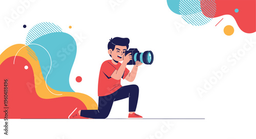 Young man in red shirt kneels and focuses while taking picture with professional camera against creative background.