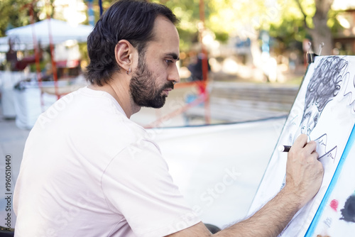 Photos Artist drawing a caricature portrait on a canvas outdoors at a street fair