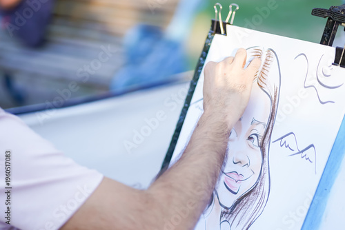 Artist drawing a caricature portrait of a woman outdoors on a sunny day