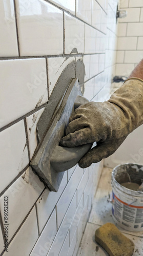 A person is using a trowel to apply grout to a wall