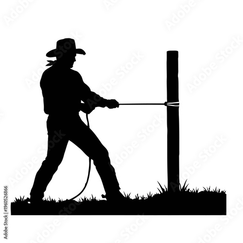 Silhouette of a cowboy tying a rope to a wooden fence post
