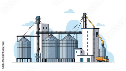Large industrial grain elevator complex used for agricultural storage with transport truck and puffy white clouds.
