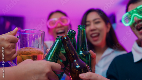 Fotografie Closeup hands multiethnic young adult Asia friend wear futuristic neon glowing glasses dance and drink alcohol beer fun hangout party in living room night indoor home