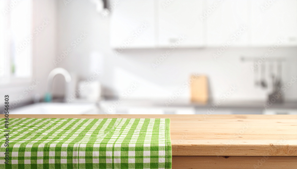 Fototapeta premium A bright wooden tabletop with a green checkered cloth, featuring a blurred modern kitchen backdrop. Ideal for culinary branding and food mockups.