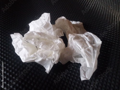 crumpled white tissue paper placed on a dark textured background. Concept of waste, hygiene, cleaning, or environmental pollution. Minimalist composition with strong contrast, 