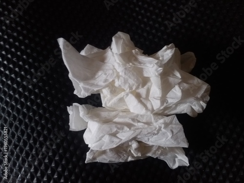 crumpled white tissue paper placed on a dark textured background. Concept of waste, hygiene, cleaning, or environmental pollution. Minimalist composition with strong contrast, 