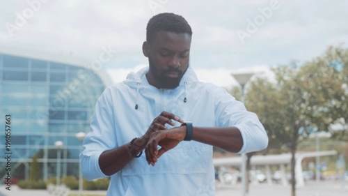 Male individual actively assesses health statistics while surrounded by parks and modern architecture