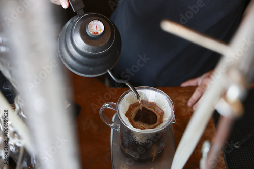 Slika na platnu Calm and focused barista pouring hot boiling water from black metal gooseneck ke