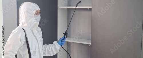 Professional pest control technician disinfects a cabinet in a residential space to ensure safety and cleanliness concept