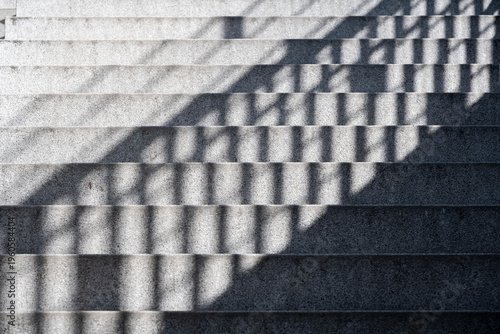 Staircase with shadows on a sunny day, a yellow stripe on the first step as a warning sign