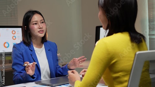 Asian businesswomen collaborating on a project at night