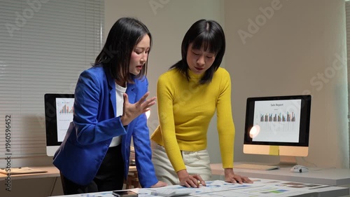 Asian businesswomen collaborating on a sales report