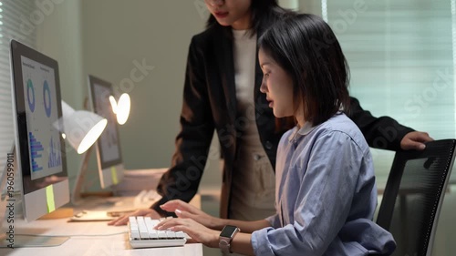 Female manager supervising employee analyzing financial data at night