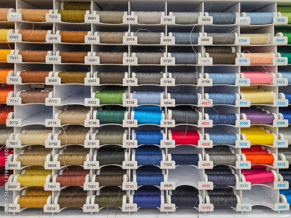 Fototapeta premium Multi-colored sewing threads on shop window. Hobby and needlework shop with collection of threads. Colored spools of threads. Full frame background