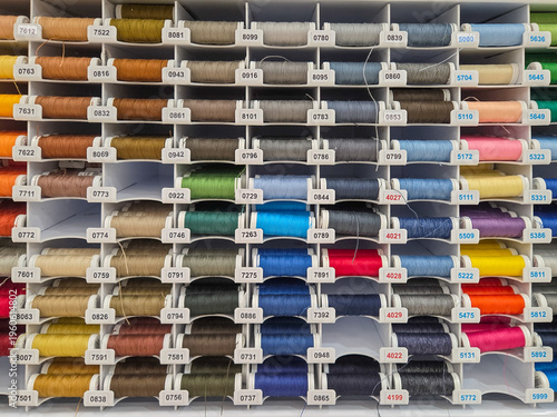 Multi-colored sewing threads on shop window. Hobby and needlework shop with collection of threads. Colored spools of threads. Full frame background
