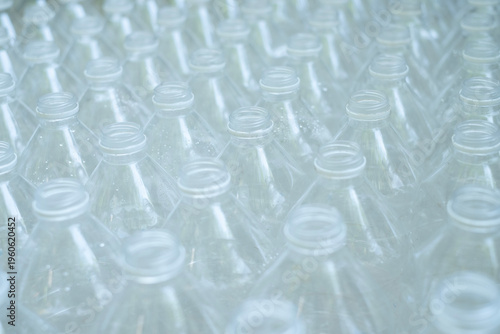 Several empty clear plastic bottles with no caps were stacked in a row.