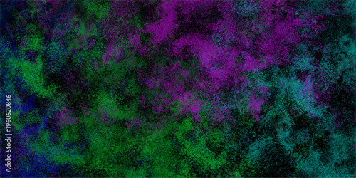 Abstract vibrant watercolor paint splatter texture with purple green and blue hues on a dark background creating a cosmic nebula effect