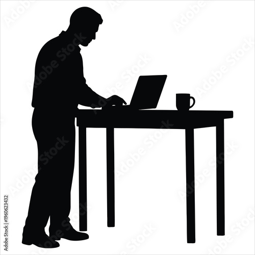 A man standing at a desk working on a laptop