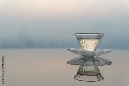 Flower-shaped glass tea cup on reflective table with city skyline