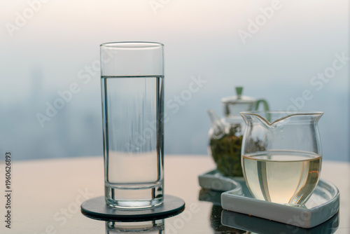 Glass tea set and a glass of water on a reflective table