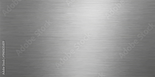 Polished silver stainless steel plate with a shiny brushed metal texture on a grey industrial aluminum surface featuring a smooth metallic pattern
