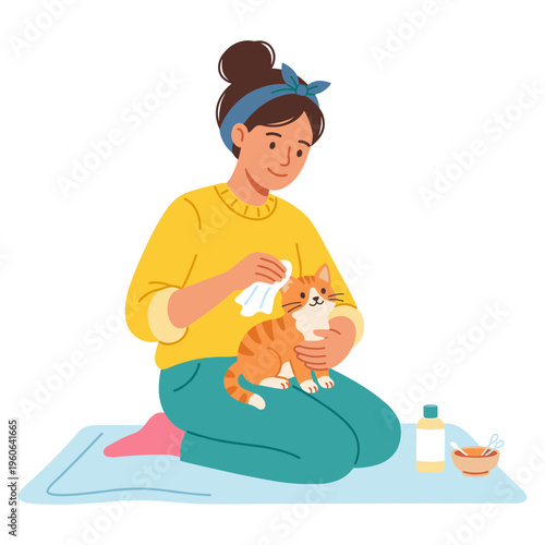 Woman gently cleans orange cat on blue mat with grooming tools nearby indoors