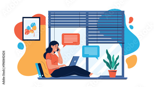 Productive woman works remotely while sitting on a window sill with her laptop and talking on a mobile phone in a home office.