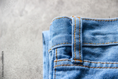 Close-up detail of blue denim jeans fabric with belt loop and orange stitching