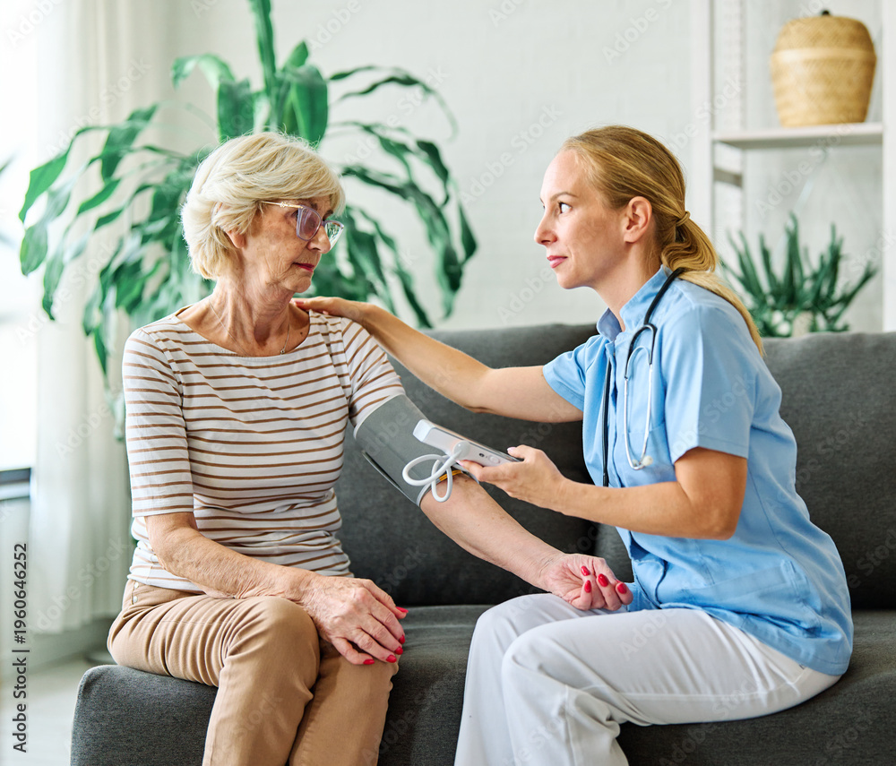 Obraz premium Doctor or nurse caregiver with senior woman using blood pressure tool at home or nursing home