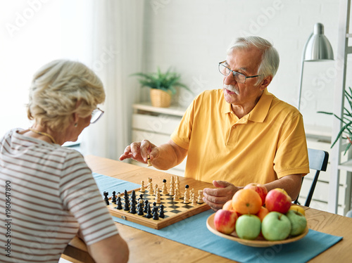 Fotografía Portrait of a happy senior couple enjoying board game playing chess at home