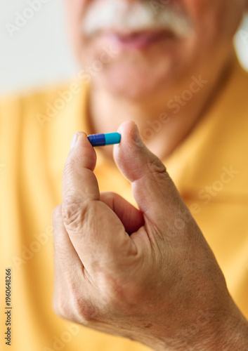 Portrait of a senior man holding drug  pill and water  at home