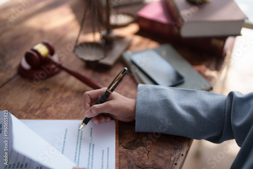 Quadro su tela Lawyer's hand holding a pen and signing a legal contract, agreement, or will, wi