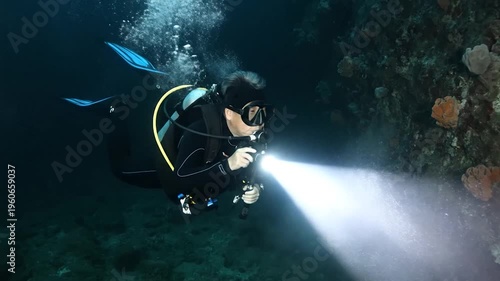A person explores the underwater world with a flashlight