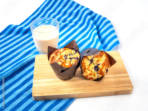 Homemade delicious freshly baked blueberry muffins with crumble topping on wooden board and a glass of milk. Dessert concept.