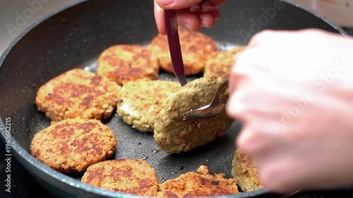 Sizzling plant-based bean patties being flipped by a female in a frying pan