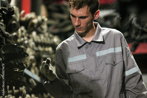 Schilderij op canvas White man technician checking used car damaged engine block at scrap yard warehouse recycle area part