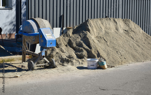 Repair work in the courtyard of the house. Сement pile and concrete mixer at the entrance to the house for construction or repair work
