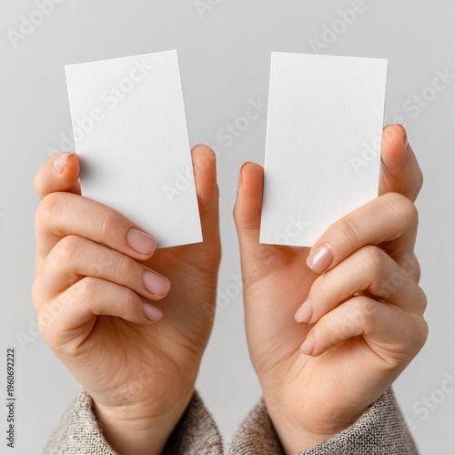 Hands holding two blank business cards against gray backdrop