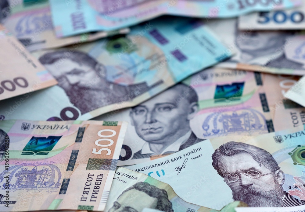 Fototapeta premium Ukrainian hryvnia money bills pile on table. Ukraine banknotes of UAH currency close up.