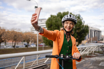 Mature woman taking a selfie while riding a scooter in the city