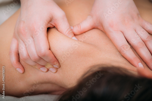 Relaxing foot massage, hands of a female massage therapist massaging female client’s foot.