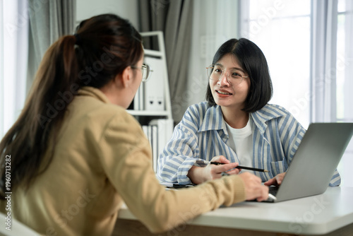 Foto Two women collaborate at a desk with a laptop  , Scene is one of collaboration a