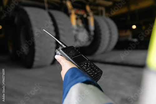 Φωτογραφία Worker using radio communicator near heavy truck wheels in depot, RC mining