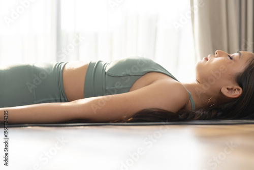 Canvas-taulu women practicing yoga corpse pose on mat, promoting relaxation, mindfulness, recovery, stress relief and healthy lifestyle through meditation and exercise