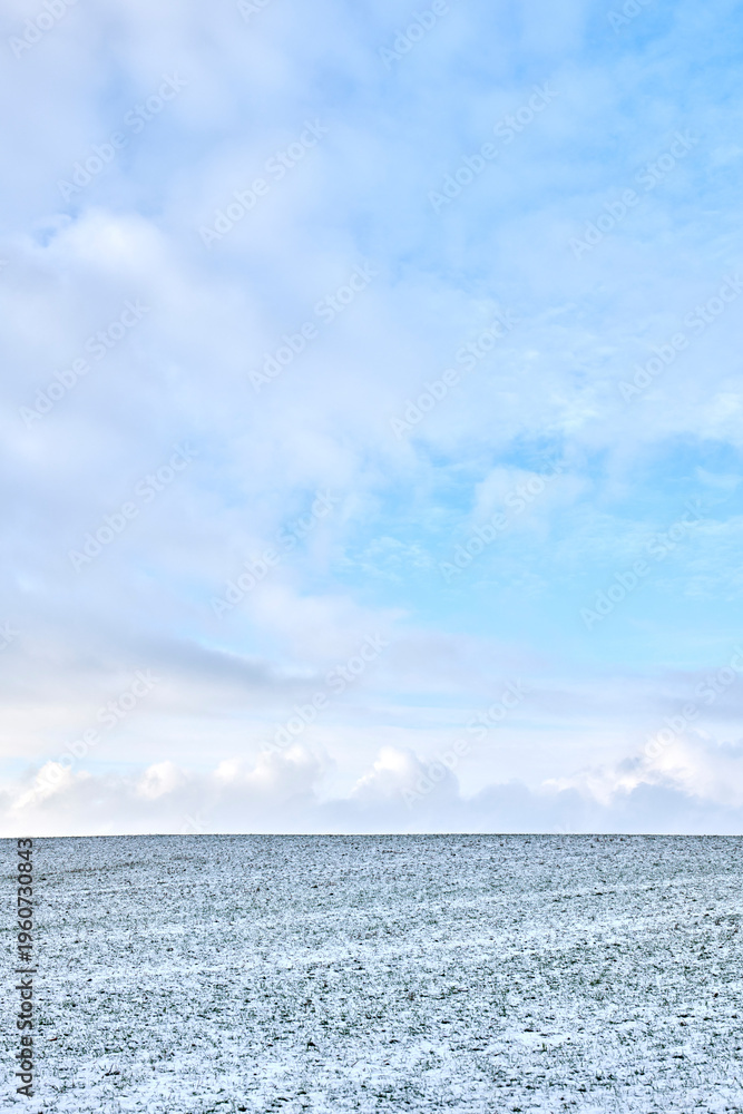 Fototapeta premium Landscape, farmland and sky with snow in nature for agriculture, dormant crops and winter season. Space, clouds and climate change with frost for soil moisture, rural farming and planting disruption
