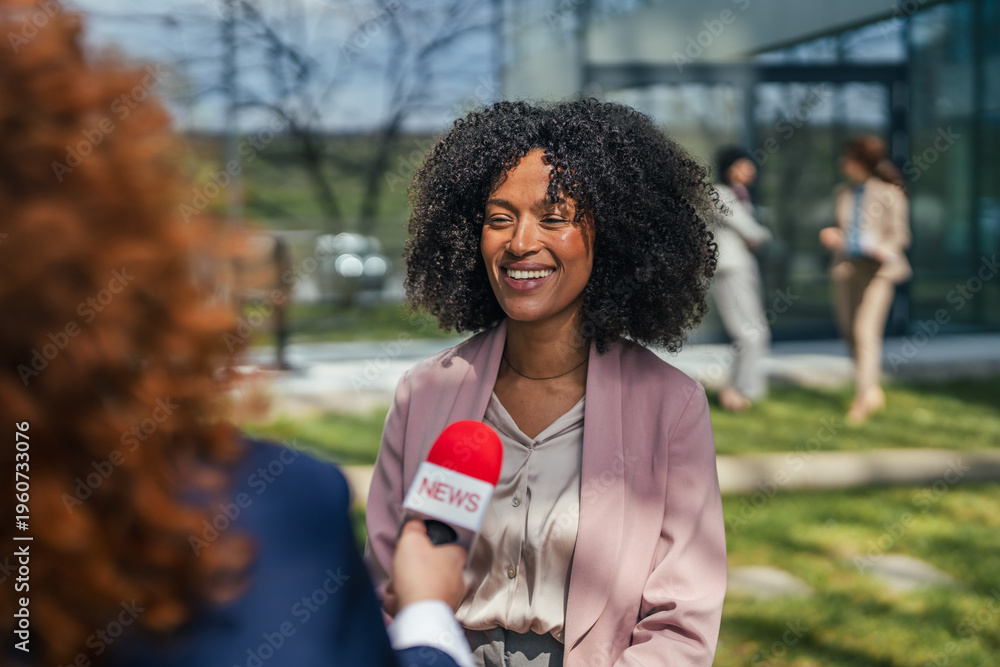 Obraz premium Smiling businesswoman giving an interview to a reporter