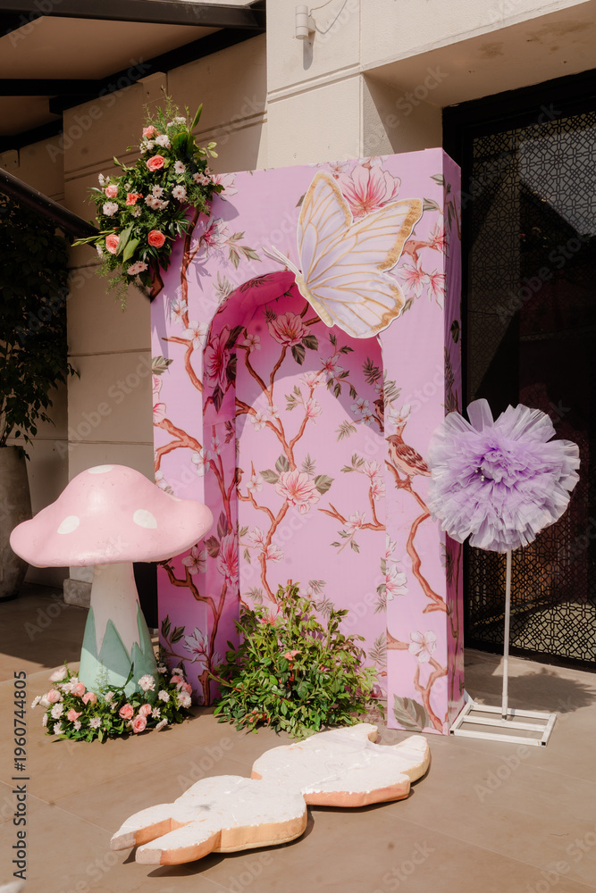 Fototapeta premium Fantasy Theme Party Decor with Mushroom and Butterfly Cutouts, Floral Wall Display, and Pastel Accents for Festive Celebration
