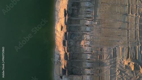 Extensive earthworks and material extraction are underway at site.truck is seen transporting sand or gravel along the water surface. project involves building infrastructure to connect channel, rial v