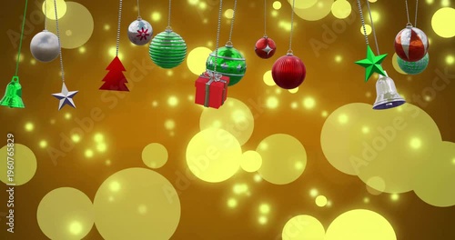 Animation of christmas baubles decoration and glowing spots on brown background